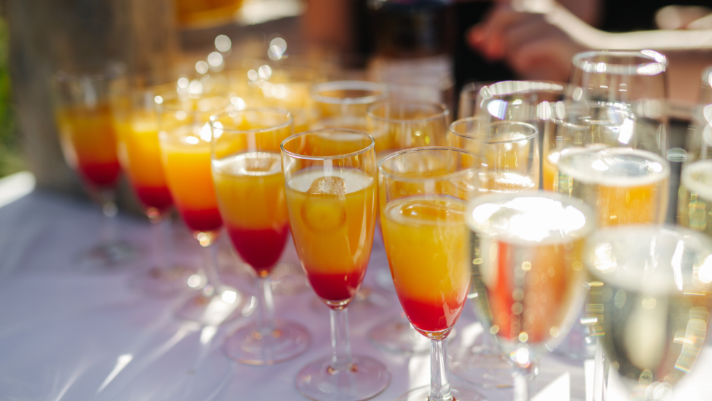 A table filled with champagne flutes containing orange fruit juice.